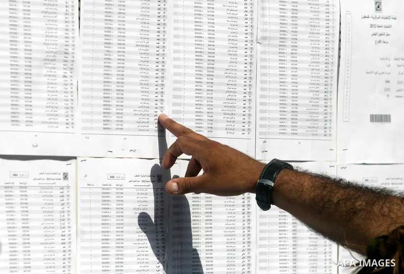 Palestinians look for his name on the registered voters' list outside a polling station in the West Bank city of Ramallah on October 20, 2012. Ballot booths opened across the West Bank as Palestinians began voting in loc...