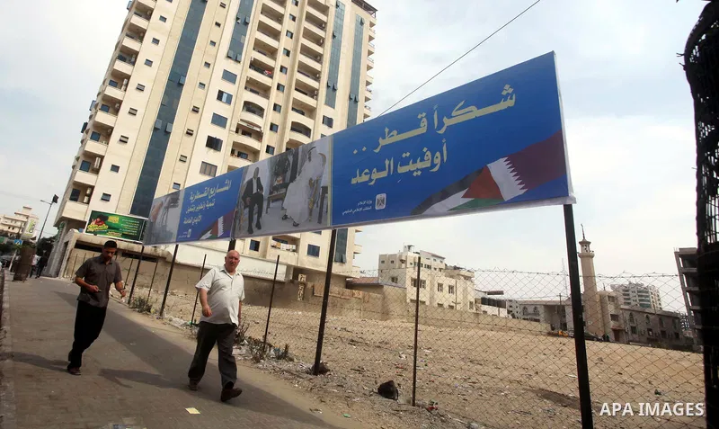 Palestinians walk pass a street placard reads in Arabic "Thank Qatar for fit promise" in Gaza city on October 21, 2012. A Qatari delegation headed by Ambassador Mohammed al-Emadi has arrived in Gaza through the Rafah cro...