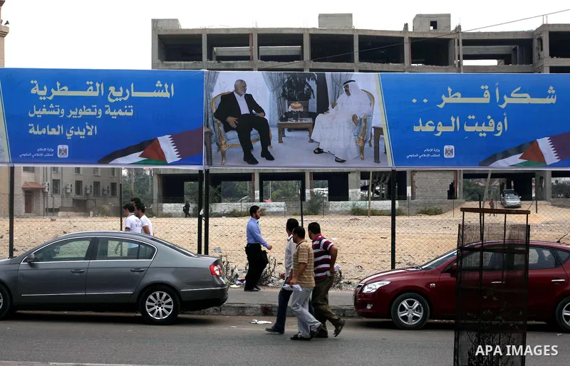 Palestinians walk pass a street placard reads in Arabic "Thank Qatar for fit promise" in Gaza city on October 21, 2012. A Qatari delegation headed by Ambassador Mohammed al-Emadi has arrived in Gaza through the Rafah cro...