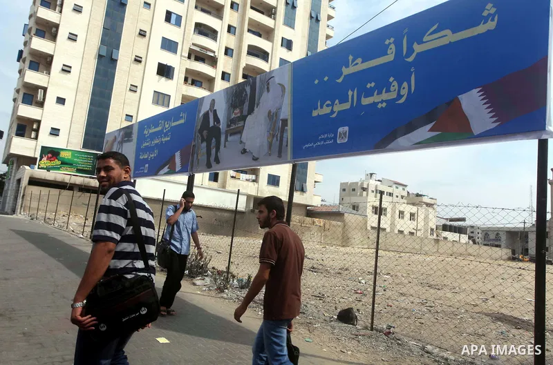 Palestinians walk pass a street placard reads in Arabic "Thank Qatar for fit promise" in Gaza city on October 21, 2012. A Qatari delegation headed by Ambassador Mohammed al-Emadi has arrived in Gaza through the Rafah cro...