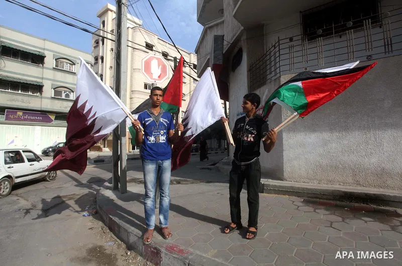 Palestinians carry the Qatari and Palestinian (red,black,white, green) flags in Gaza City on October 21, 2012, the day before the Emir of Qatar's official visit to the strip. Emir of Qatar Hamad bin Khalifa Al Thani visi...