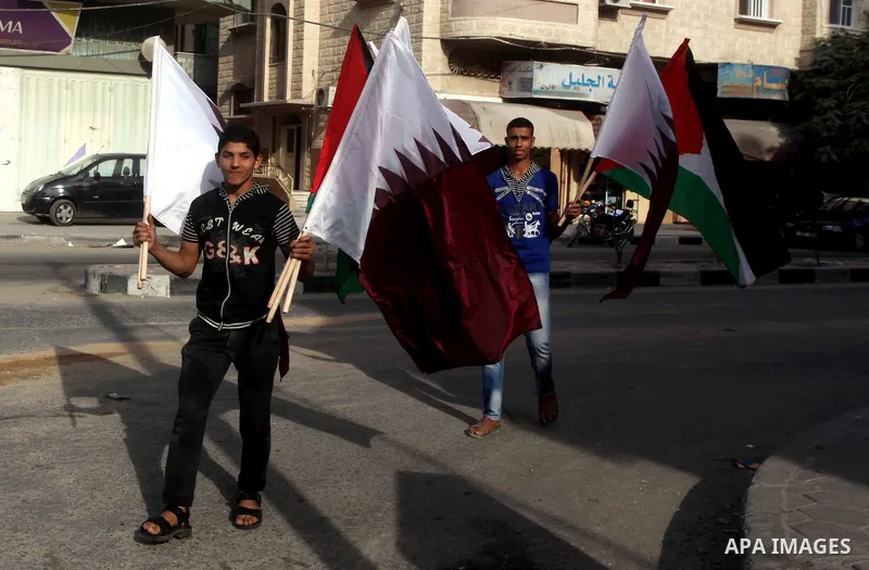 Palestinians carry the Qatari and Palestinian (red,black,white, green) flags in Gaza City on October 21, 2012, the day before the Emir of Qatar's official visit to the strip. Emir of Qatar Hamad bin Khalifa Al Thani visi...