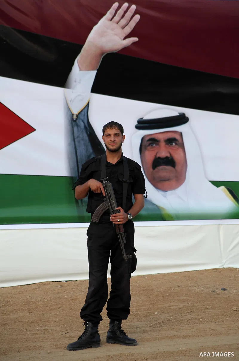 A Palestinian security officer stands near a poster of Qatar's Emir Sheikh Hamad bin Khalifa al-Thani in Gaza city on October 22, 2012. The Qatari emir will visit Gaza on October 23 in the first such visit by an Arab lea...