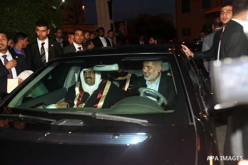 Qatari Emir Sheikh Hamad bin Khalifa al-Thani sits beside Gaza's prime minister Ismail Haniya as he drives a car surrounded by bodyguards in Gaza City on October 23, 2012. The Emir of Qatar entered the Gaza Strip on Tues...