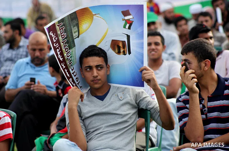 Palestinian Hamas supporters hold posters of the Emir of Qatar Sheikh Hamad bin Khalifa al-Thani, not pictured, as they wait for him to give a speech at the Palestine stadium in Gaza City, Tuesday, Oct. 23, 2012. The emi...