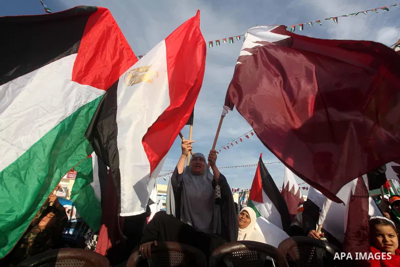 Palestinian Hamas supporters wave Qatari and Palestinian flags as others hold posters of the Emir of Qatar Sheikh Hamad bin Khalifa al-Thani, not pictured, as they wait for him to give a speech at the Palestine stadium i...