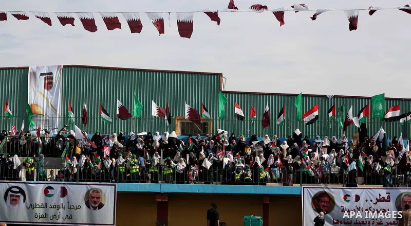 Palestinian Hamas supporters wave Qatari and Palestinian flags as others hold posters of the Emir of Qatar Sheikh Hamad bin Khalifa al-Thani, not pictured, as they wait for him to give a speech at the Palestine stadium i...