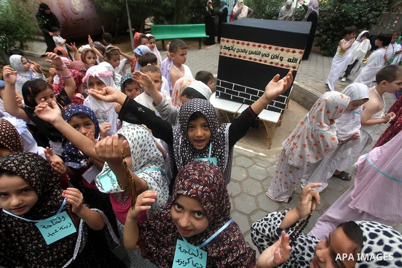 Palestinian children gather around a makeshift cube representing the holy Kaaba in Gaza City, on October 24, 2012, as part of training children how to perform Hajj pilgrimage. Muslims from around the world flood Saudi ci...