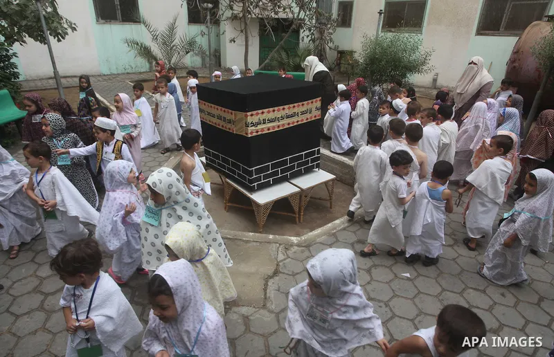 Palestinian children gather around a makeshift cube representing the holy Kaaba in Gaza City, on October 24, 2012, as part of training children how to perform Hajj pilgrimage. Muslims from around the world flood Saudi ci...