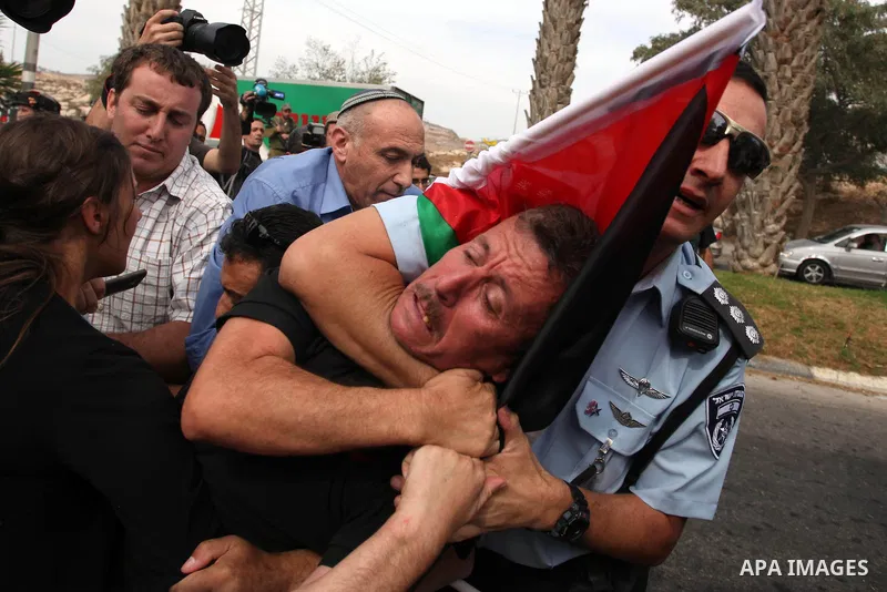 A Palestinian activist is arrested by Israeli soldiers as dozens of Palestinians block the entrance to branch of the Rami Levy supermarket opened in Shaar Binyamin close to the city of Ramallah in the Israeli occupied Pa...