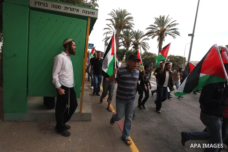 Palestinian activists hold up the Palestinian flag as they rally outside a branch of the Rami Levy supermarket which opened in Shaar Binyamin Jewish settlement close to the city of Ramallah in the Israeli occupied Palest...