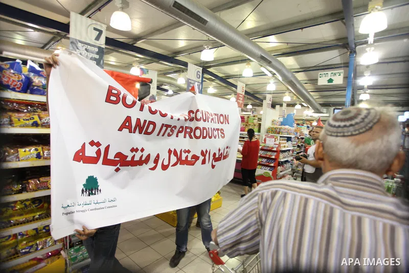 Palestinian activists hold up the Palestinian flag as they rally inside a branch of the Rami Levy supermarket which opened in Shaar Binyamin Jewish settlement close to the city of Ramallah in the Israeli occupied Palesti...