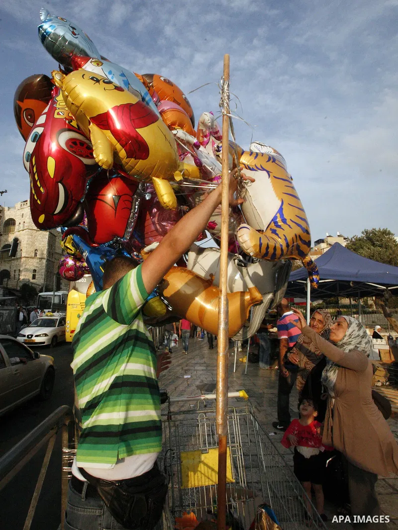 A Palestinian man sells ballons during preparations for the Eid al-Adha, in the West Bank city of Jerusalem, on October 25, 2012. Muslims around the world prepare to celebrate Eid Al-Adha, which according to the lunar ca...