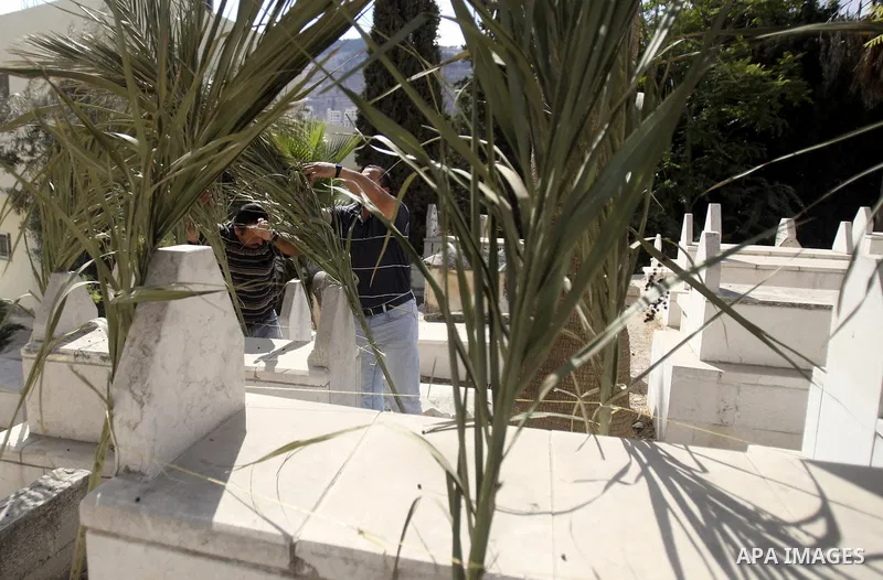 Palestinians put palm fronds on the graves of their relatives ahead of Muslim festival of Eid al-Adha, in the West Bank city of Nablus, on October 25, 2012. Muslims around the world prepare to celebrate Eid Al-Adha, whic...