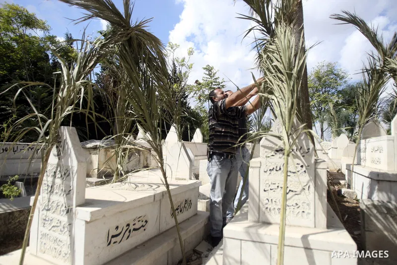Palestinians put palm fronds on the graves of their relatives ahead of Muslim festival of Eid al-Adha, in the West Bank city of Nablus, on October 25, 2012. Muslims around the world prepare to celebrate Eid Al-Adha, whic...