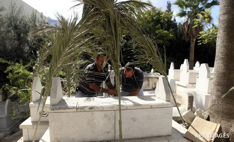 Palestinians put palm fronds on the graves of their relatives ahead of Muslim festival of Eid al-Adha, in the West Bank city of Nablus, on October 25, 2012. Muslims around the world prepare to celebrate Eid Al-Adha, whic...