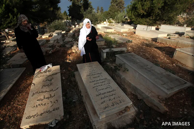 Palestinians visit the graves of relatives at a cemetery in the West Bank city of Ramallah on the first day of Eid al-Adha, on October 26, 2012 as Muslims worldwide commemorate Eid al-Adha, or the Feast of the Sacrifice,...