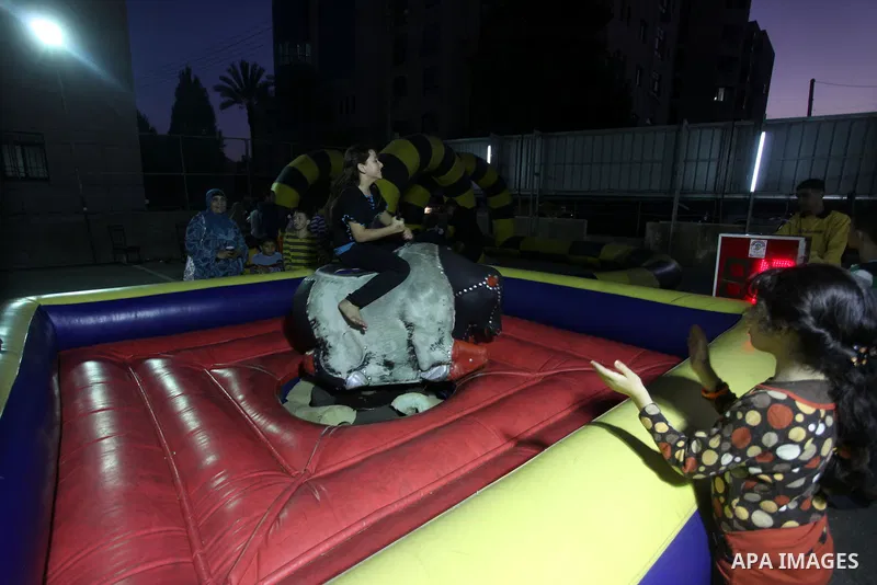 Palestinian children enjoy a ride at an amusement park during the second day of Eid al-Adha in the West Bank city of Ramallah, oct 27, 2012. Muslims around the world celebrate Eid-al-Adha, marking the end of the haj, by...