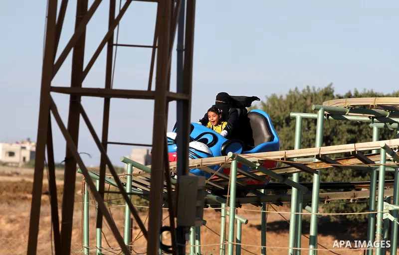 Palestinians enjoy themselves at an amusement park in Gaza City as the Muslim world celebrates the third day of the Eid al-Adha holiday on October 28, 2012. Eid al-Adha or "Feast of the Sacrifice" marks the end of the an...