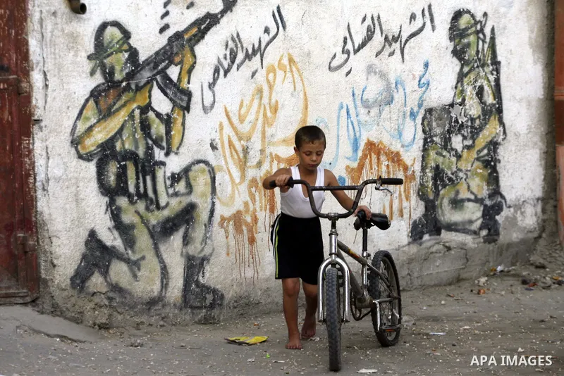 A Palestinian child plays in front of a wall graffiti, in Rafah refugee camp southern the Gaza strip, Oct. 30, 2012. In the aftermath of the Israeli military Operation Cast Lead in 2008/2009, Palestinian refugees in Gaza...
