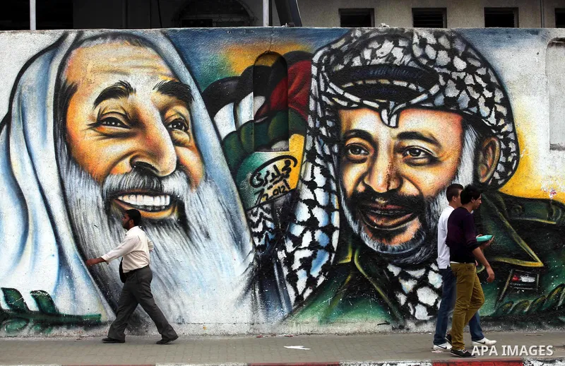 Palestinians passe by a mural depicting late Palestinian leader Yasser Arafat in Gaza City on Oct. 31, 2012. Palestinian authorities confirmed the November timetable to exhume the remains of former Palestinian leader Yas...