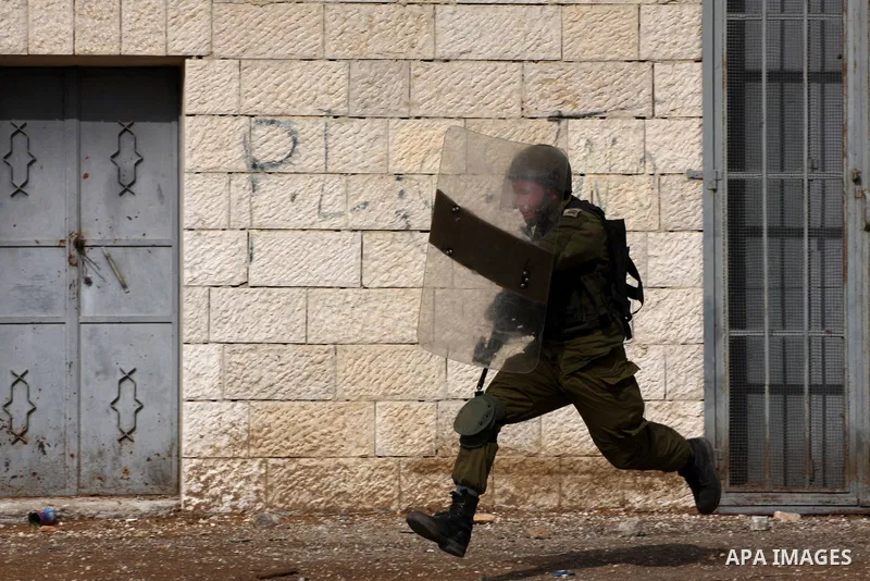 An Israeli soldier chases Palestinian protesters during clashes following a demonstration marking the anniversary of Balfour Declaration, in the village of Kfar Qaddum, near the West Bank city of Nablus on November 02, 2...