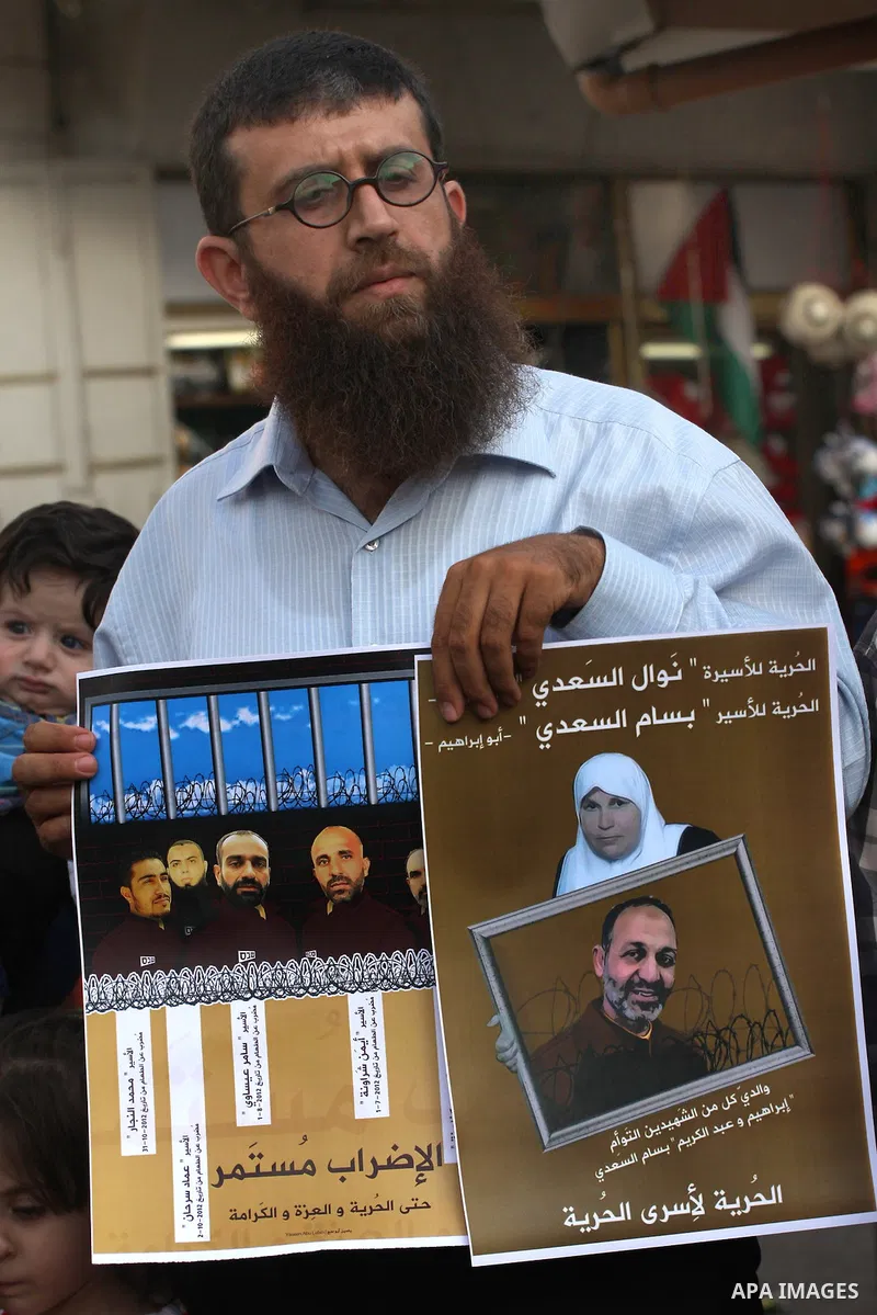 Palestinian former prisoner Adnan Khader holds a poster of Palestinian prisoners during a protest calling for the release them from Israeli jails and in support of prisoners on hunger strike, in the West Bank city of Nab...