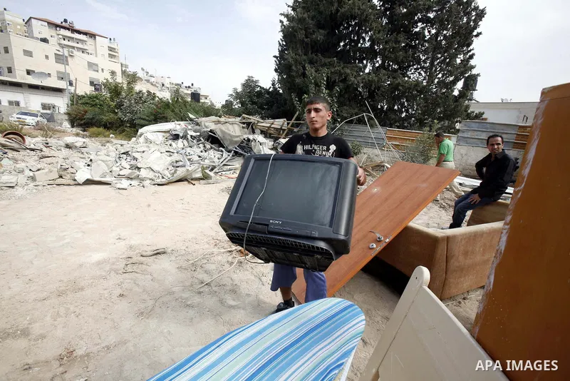 A Palestinian man carries furniture from the rubble of his house after it was demolished by Jerusalem municipality workers in the east Jerusalem neighborhood of al-Tur on November 5, 2012. Israel's policy of house demoli...