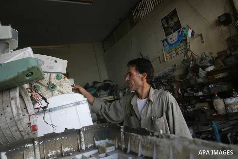 A Palestinian man repairs a washer at his workshop in Rafah southern in Gaza City on November 6, 2012. Photo by Eyad Al Baba