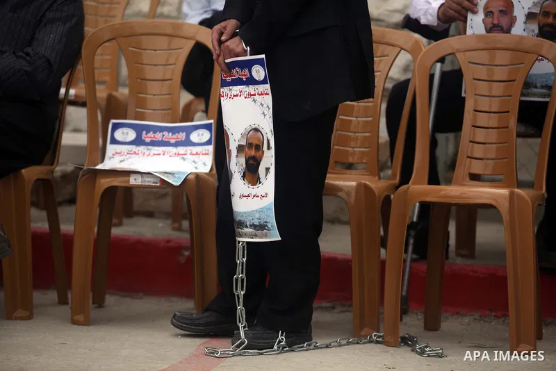A Palestinian man holds picture of prisoners held in Israeli jails during a sit-in outside the Red Crescent offices near the West Bank city of Ramallah on Nov. 6, 2012. Photo by Issam Rimawi