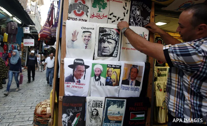 A Palestinian man pastes posters of U.S. President Barack Obama on his shopfront during the first day of U.S. presidential elections, in Jerusalem on 06 November 2012. Recent polls show that U.S. President Barack Obama a...