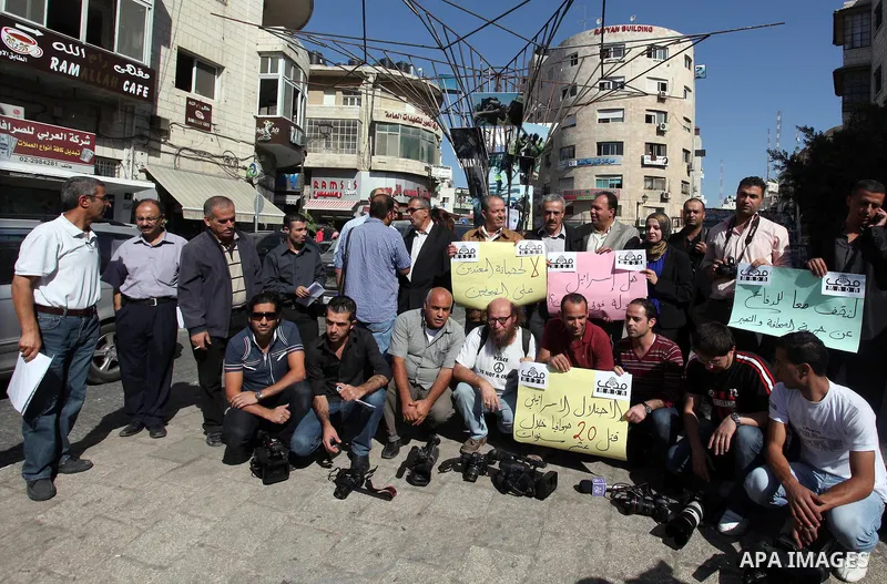 Palestinian journalists hold placards during a protest against the violations of their rights by Israeli authorities on the international day to end impunity, in the West Bank city of Ramallah on November 08, 2012. In th...