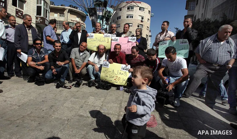 Palestinian journalists hold placards during a protest against the violations of their rights by Israeli authorities on the international day to end impunity, in the West Bank city of Ramallah on November 08, 2012. In th...