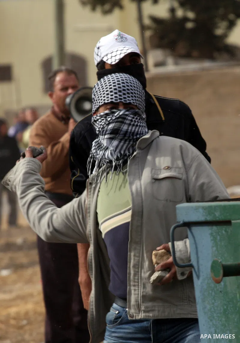 A Palestinian protester throws stones towards Israeli soldiers during clashes following a demonstration against the expropriation of Palestinian land by Israel in the village of Kfar Qaddum, near the occupied West Bank c...