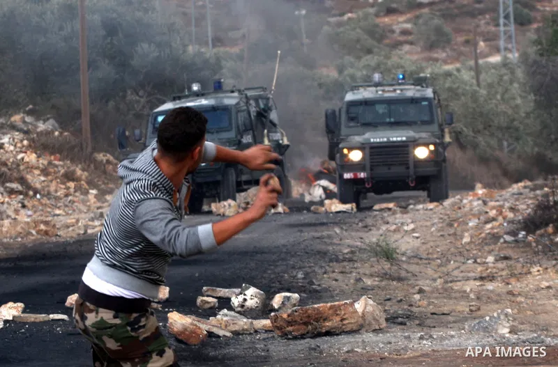 A Palestinian protester throws stones towards Israeli soldiers during clashes following a demonstration against the expropriation of Palestinian land by Israel in the village of Kfar Qaddum, near the occupied West Bank c...