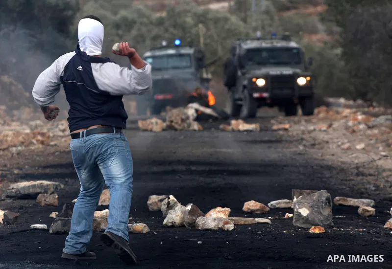 A Palestinian protester throws stones towards Israeli soldiers during clashes following a demonstration against the expropriation of Palestinian land by Israel in the village of Kfar Qaddum, near the occupied West Bank c...
