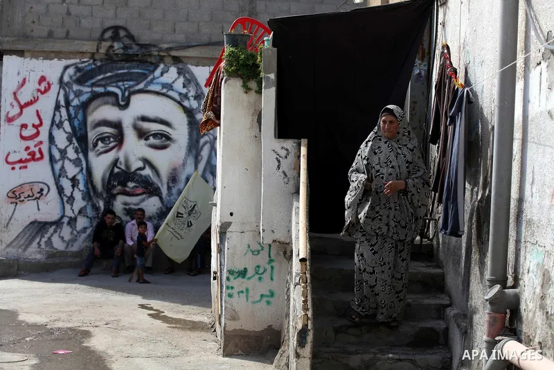 A Palestinian woman walks in front of a mural of the Palestinian Leader Yasser Arafat in Gaza City, on November 10, 2012. "The Eighth anniversary of the departure of the founding leader". Photo by Majdi Fathi