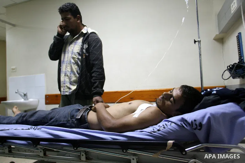 Palestinians lie on stretchers as they receive treatment at a hospital in Khan Yunis, southern Gaza Strip, after being wounded in Israeli shelling as clashes erupted along the border on November 10, 2012. Two Palestinian...