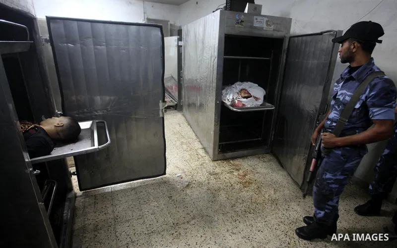 Palestinian policeman stand by the body in a hospital morgue in Gaza City November 10, 2012. Israeli tank shells killed at least four Palestinians and wounded 25 in the Gaza Strip on Saturday after an apparent attack on...