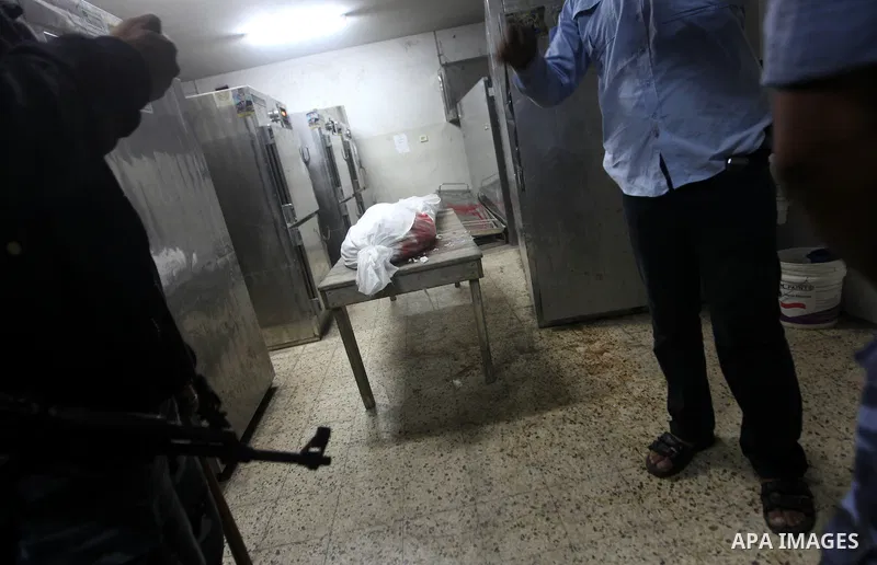 Palestinian policeman stand by the body in a hospital morgue in Gaza City November 10, 2012. Israeli tank shells killed at least four Palestinians and wounded 25 in the Gaza Strip on Saturday after an apparent attack on...