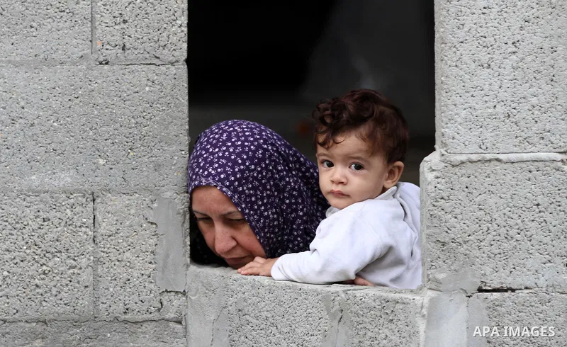A Palestinian woman looks through a window at the funeral at the Shati refugee camp in Gaza City, Sunday, Nov. 11, 2012. Hostilities along the Gaza-Israel border escalated sharply over the weekend, with bombardments from...
