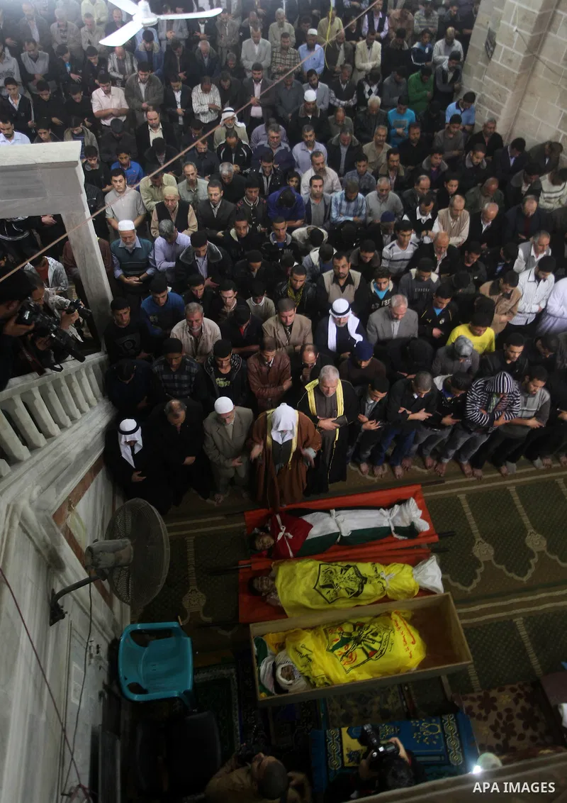 Palestinians pray at a mosque next to the bodies of three Palestinians who were killed in Israeli shelling on Saturday during their funeral in Gaza City November 11, 2012. Israel said it was poised to escalate attacks on...