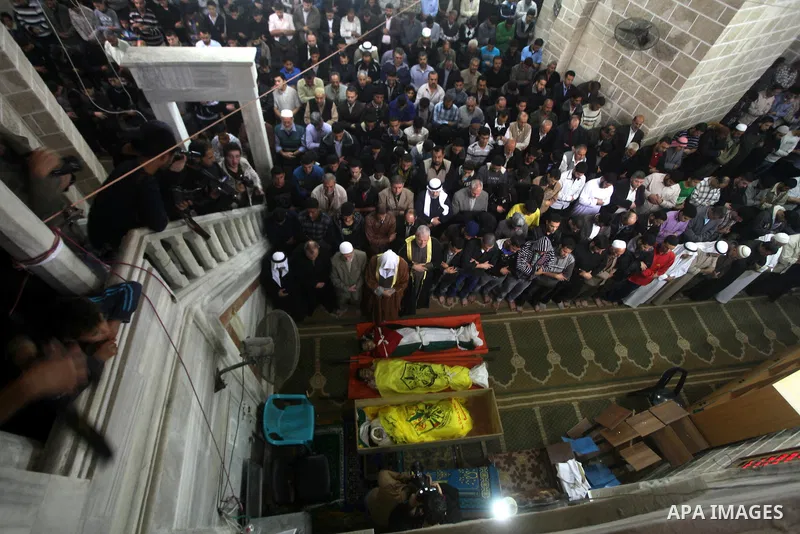 Palestinians pray at a mosque next to the bodies of three Palestinians who were killed in Israeli shelling on Saturday during their funeral in Gaza City November 11, 2012. Israel said it was poised to escalate attacks on...