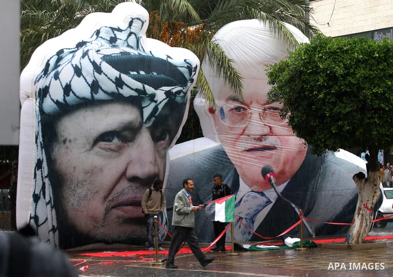 Palestinians walk pass a mural of the late Yasser Arafat and current Palestinian President Mahmoud Abbas during the eighth anniversary of the death of the late leader Yasser Arafat, in the West Bank city of Nablus on Nov...