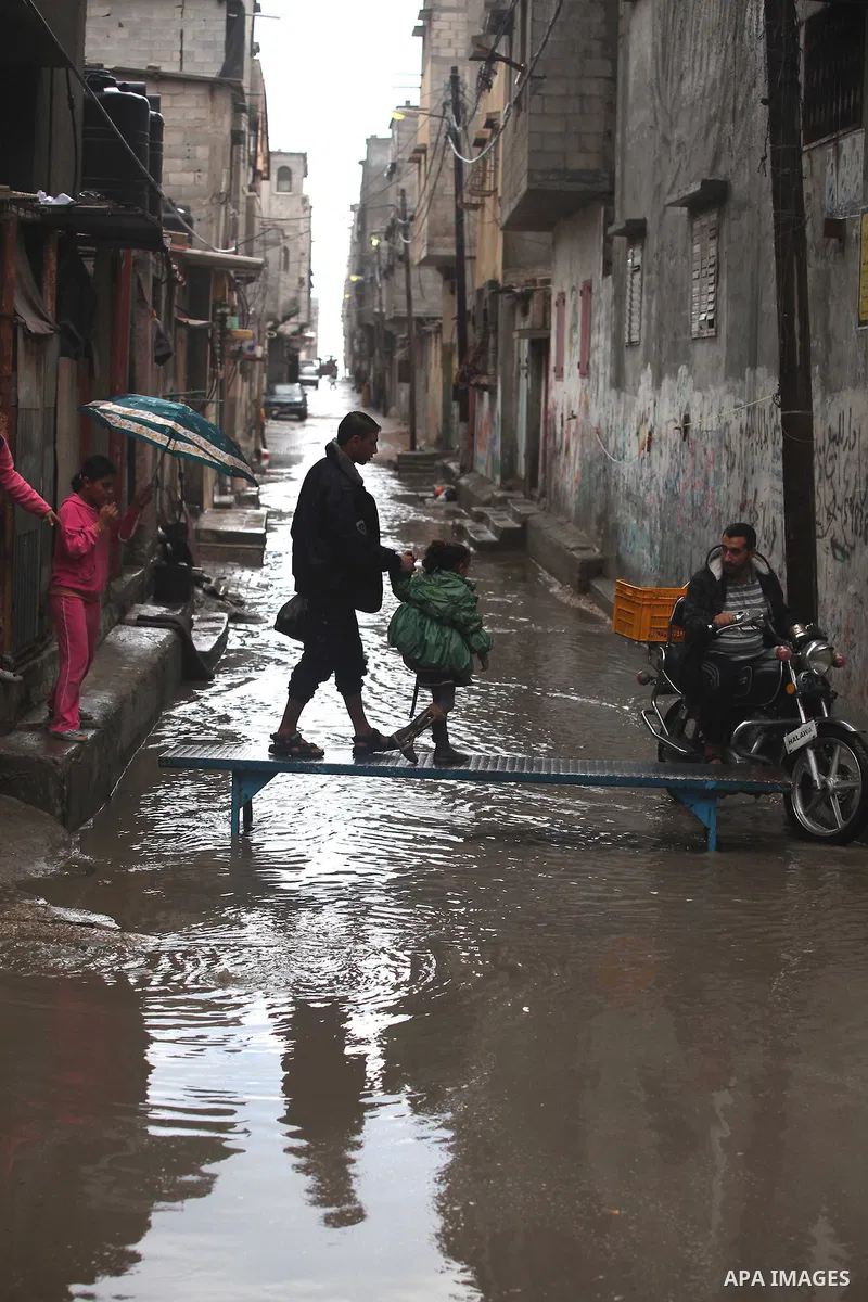 Palestinians cross a flooded street in al-Shatee refugee camp in Gaza City on November 11, 2012. In the aftermath of the Israeli military Operation Cast Lead in 2008/2009, Palestinian refugees in Gaza camps need more sup...