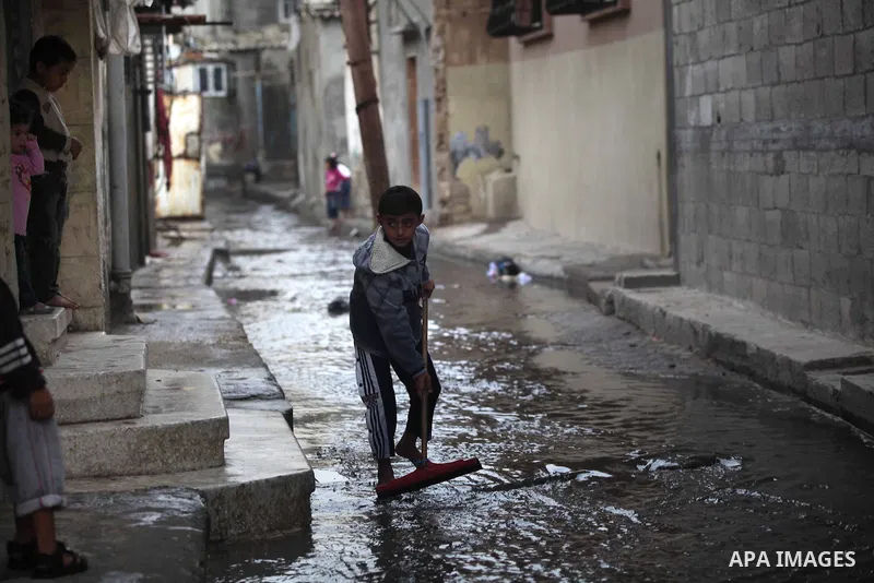 A Palestinian boy cleans the flooded street in front of his house in al-Shatee refugee camp in Gaza City on November 11, 2012. In the aftermath of the Israeli military Operation Cast Lead in 2008/2009, Palestinian refuge...