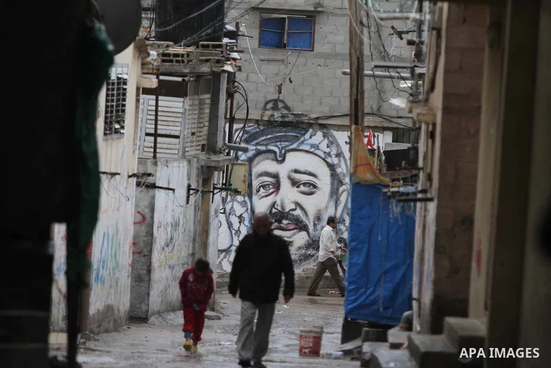 Palestinians walk past a mural of the late Palestinian leader Yasser Arafat in al-Shatee refugee camp in Gaza City on November 11, 2012. Palestinians are coordinating with Russia, as well as Swiss and French experts, on...