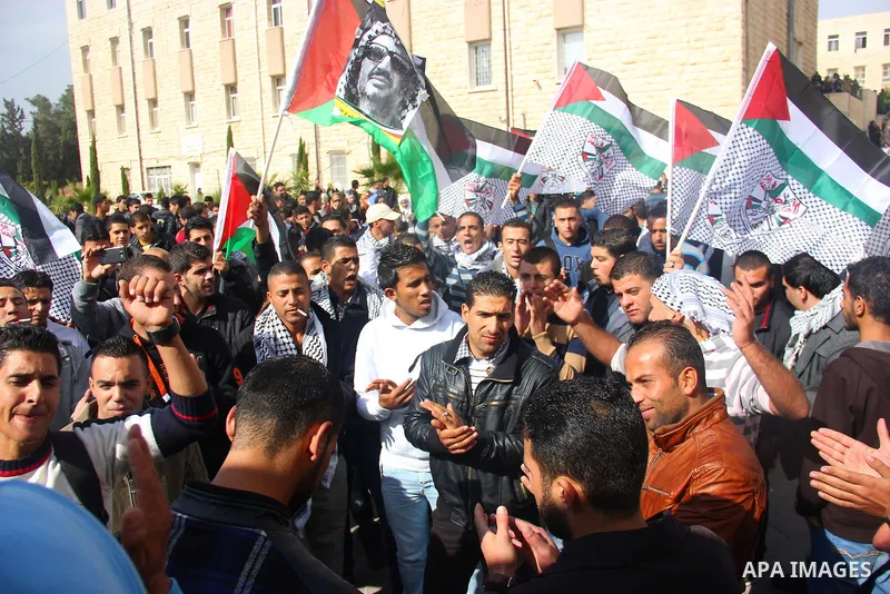 Palestinians hold-up national flags and posters of the late Palestinian leader Yasser Arafat mark the eighth anniversary of his death, in the West Bank city of Hebron on November 11, 2012. Palestinians are coordinating w...