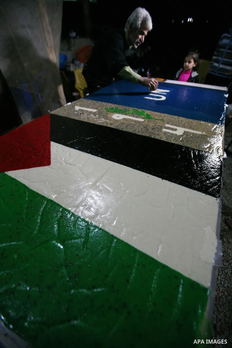 Farmer Suhail Brighit paints a Palestinian flag with the United Nations "UN" flag in support Palestinian President Mahmoud Abbas's step to seek non-member observer status for Palestine at the United Nations, in the West...