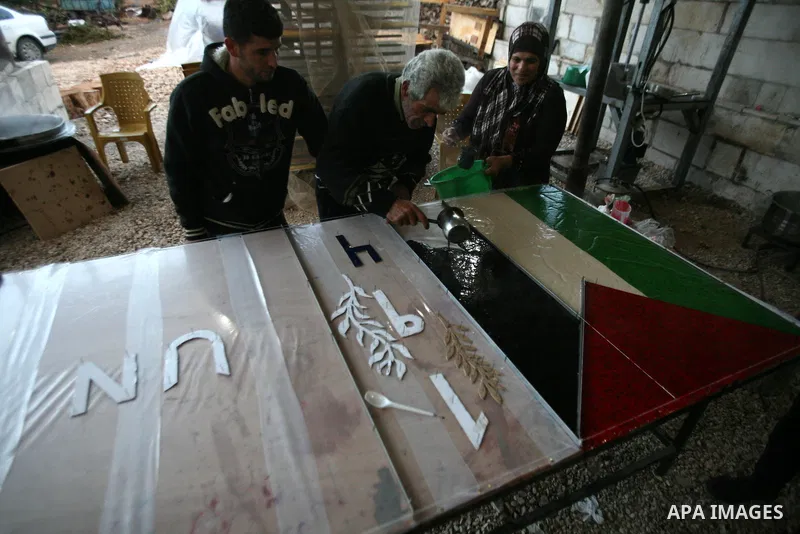 Farmer Suhail Brighit paints a Palestinian flag with the United Nations "UN" flag in support Palestinian President Mahmoud Abbas's step to seek non-member observer status for Palestine at the United Nations, in the West...